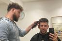 Owner Tom Hodges gets a trim from fellow barber Jake Beadle