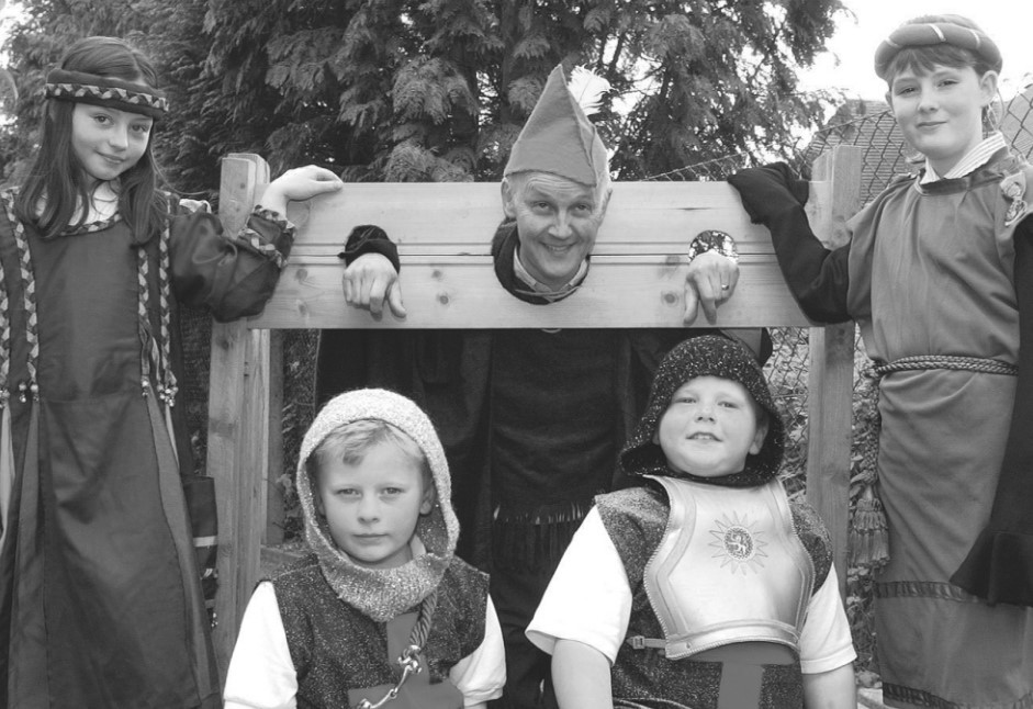 Colwall Primary School headteacher Richard Southall in the stocks before the annual May Fair in 2002 with, from left, Becky Doyle, Nicholas Heatherington, Shand Hitchings and Louise Jones